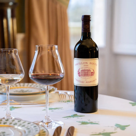 Bottle of Pavillon Rouge wine with two glasses on a table.